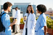 © BONNINSTUDIO/Stocksy - Medical team during conversation on hospital terrace
