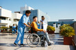 © BONNINSTUDIO/Stocksy - Wheelchair patient in hospital with male nurse assistant