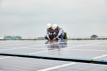 Two Asian workers are inspecting solar photovoltaic cells