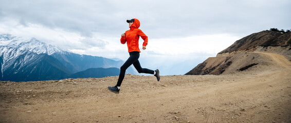 Wall Mural - Woman trail runner cross country running at high altitude mountains