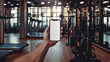 Cropped image of sportswoman holding smartphone with blank screen in gym