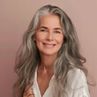 Gorgeous mature woman with long gray hair and smooth healthy skin smiling happily in beauty and cosmetics skincare advertising concept