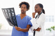 © Katie/peopleimages.com - Doctor, nurse and study xray for health, collaboration for surgery and treatment plan with anatomy. Black people review abdominal CAT scan, MRI or radiology, medicine and surgeon with team at clinic