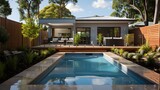 Fototapeta Londyn - The fenced backyard of a newly built house features a rectangular swimming pool with tan concrete borders