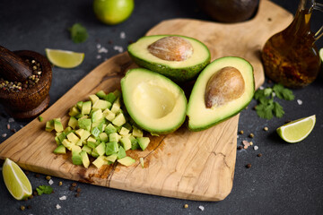 Wall Mural - Halved green avocado fruit on wooden cutting board at domestic kitchen