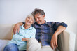© M S/peopleimages.com - Old couple, hug and relax on sofa with happiness at home, love and security with comfort for bonding. Marriage, partner and retirement together with smile, trust and loyalty with people in lounge