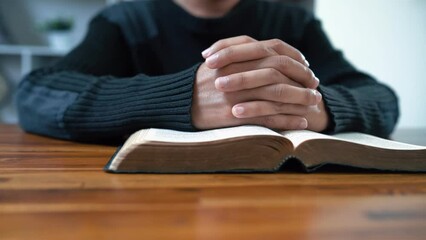 Wall Mural - Close up hands praying on Bible at wooden table in morning, Christian concept.