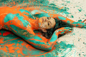 Wall Mural - portrait and upper body of expressive sexy woman lying naked elegant on the floor in turquoise blue color abstract painted bodypainting woman on the ground