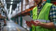 © jirayut - Close-up of man in safety vest hands using tablet checking information or inventory while standing in the warehouse