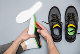 Fototapeta Przestrzenne - Close up of man hands fitting orthopedic insoles on a gray background.