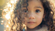 A young child with mesmerizing eyes amidst sunlit curls.