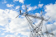 © Austockphoto - Metal power pole structure with powerlines in sunlight against cloudy blue sky