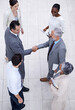 © YATrainer/peopleimages.com - Team, handshake and happy business people with CEO for deal, collaboration or partnership agreement for diverse financial advisors. Top view, shaking hands and group in office meeting for acquisition