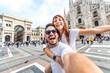 © Davide Angelini - Happy couple taking selfie in front of Duomo cathedral in Milan, Lombardia - Two tourists having fun on romantic summer vacation in Italy - Holidays and traveling lifestyle concept