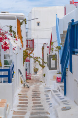 Wall Mural - narrow side street with traditional whitewashed walls and blue accents in Mykanos Greece. traditional windmill on the sea shore and colorful restaurants