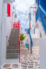 Wall Mural - narrow side street with traditional whitewashed walls and blue accents in Mykanos Greece. traditional windmill on the sea shore and colorful restaurants