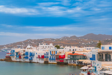 Wall Mural - narrow side street with traditional whitewashed walls and blue accents in Mykanos Greece. traditional windmill on the sea shore and colorful restaurants