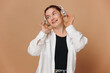 © anatoliycherkas - Modern woman smiling with braces on her teeth and listening to music in headphones on a beige background