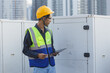 © eakgrungenerd - Man engineer using tablet working at rooftop building construction. Male technician worker working checking HVAC of office building. Engineering installing large air conditioning system.