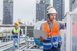 Man engineer holding laptop working at rooftop building construction. Male technician worker working checking hvac of office building. Engineering installing large air conditioning system.