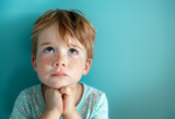 Fototapeta  - Little red-haired boy with freckles looking up praying or making a wish isolated on blue background with copyspace