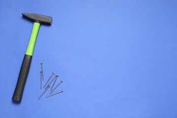 Wall Mural - Hammer and metal nails on blue background, top view. Space for text