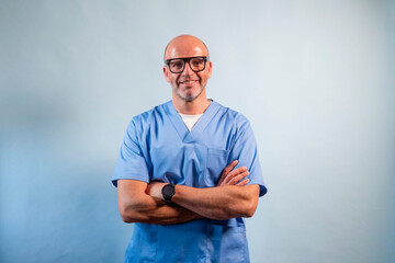 Portrait of a physiotherapist in light blue gown and glasses looking at camera in studio.