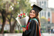 © MarGa - Joyful Latina Graduate Holding Flowers at University Campus
