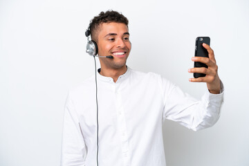 Wall Mural - Telemarketer Brazilian man working with a headset isolated on white background making a selfie