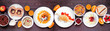 Fun child theme breakfast table scene with assorted animal themed foods. Top down view on a dark wood banner background. Pancakes, oatmeal, toast, fruit and cereal.