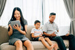 © sorapop - Parents kids engaged with laptops and phones ignoring familial bonding. An Asian family's device dependence portrays the challenges of internet addiction. ignores togetherness
