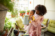 © Marko Geber - Young mother and daughter watering plants and flowers on the balcony of their apartment