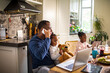 © Marko Geber - Single father having breakfast with his two young daughters while talking on the phone and working on his laptop