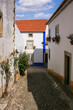 Kleine Gasse entlang von alten weißen Häusern in einem kleinen portugiesischen Dorf, mediteranes Flair