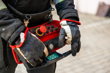  Close-up of Industrial Worker Operating a Remote Control Panel with Protective Gloves