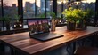 A laptop is open on a wooden table in front of a potted plant