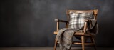 Fototapeta  - A wooden chair with a plaid pillow and blanket sits on the hardwood flooring, adding a cozy touch to the rooms decor