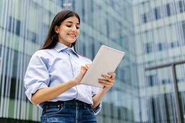 Portrait of a successful business woman using digital tablet over corporate modern business building