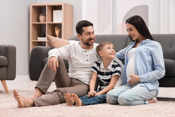 Poster - Pregnant woman spending time with her son and husband at home. Happy family