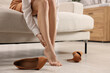 © New Africa - Woman suffering from leg pain after wearing high heels at home, closeup