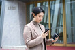 © zhouyilu - Young Professional Woman Using Smartphone Outdoors