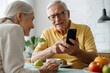 senior couple wine together,woman man senior couple home mobile phone phone retirement communication breakfast wife husband elderly together texting smartphone using modern message two internet online