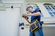 © romaset - A technician sets up a CCTV camera on the facade of a residential building.