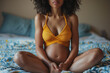 © Stock'd  - anonymous black woman's torso in early pregnancy sitting on bed, colorful pattern bed clothes