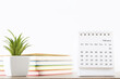 Calendar page with green plant and stack of notepads on white background