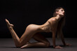 Athletic natural woman body on dark background. Nude woman Yoga.	