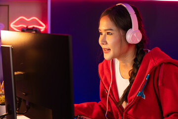 Host channel of smiling beautiful Asian girl streamer playing online game wearing headphone talking with viewers media online recording phone. Esport skilled team players in neon blue room. Stratagem.