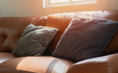 Comfortable orange leather sofa and pillows with real soft morning sunlight