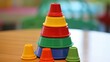 Playful stacking cups forming a colorful pyramid on a lively green playmat, symbolizing early learning.