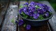 Purple violets in a black plastic bowl on a wet wooden garden table